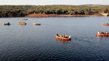 Un grupo de barcos en un lago tranquilo con una orilla boscosa al fondo.