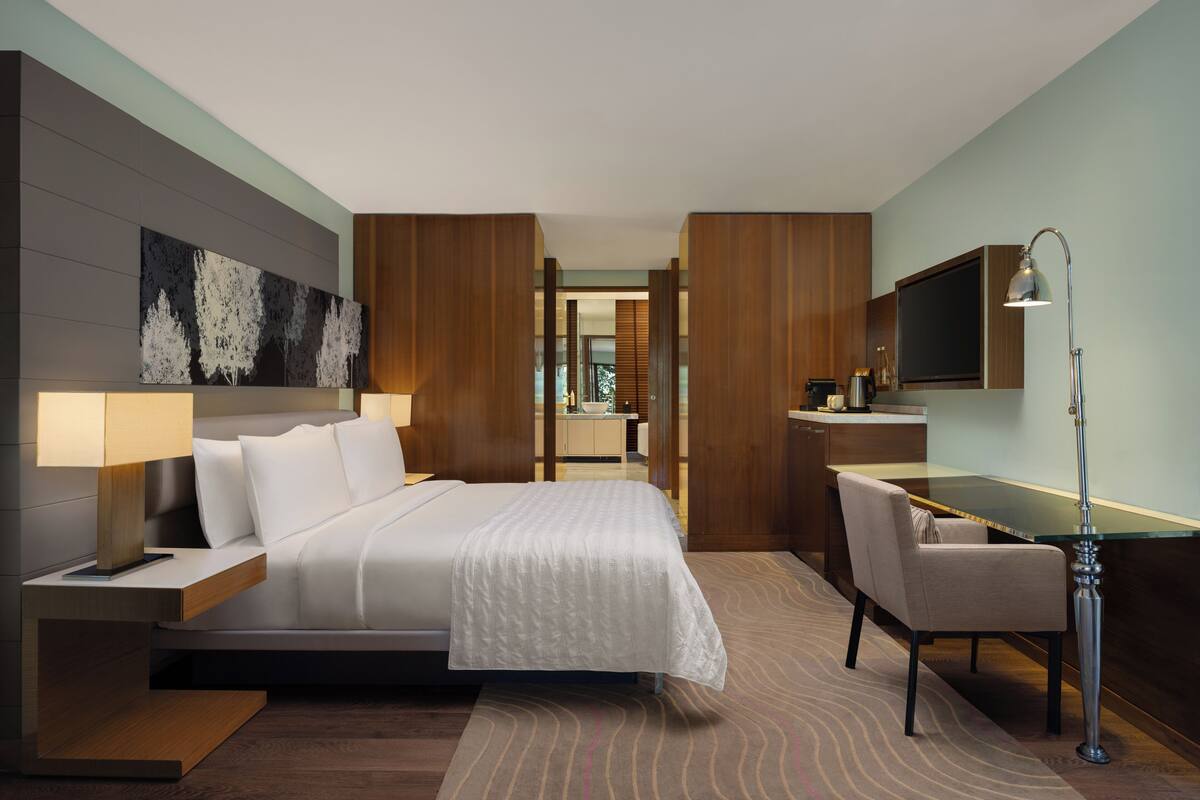 Une chambre d’hôtel moderne équipée d’un lit, d’un bureau, d’une chaise et d’un téléviseur.