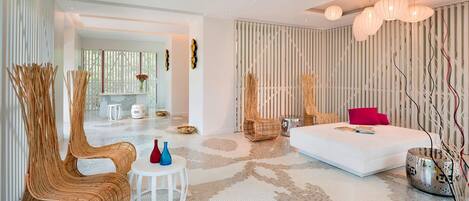 A modern living room with a white sofa, wicker chairs, a small round table, and a decorative vase.