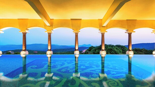 Una piscina infinita con una vista despejada de las montañas al fondo.