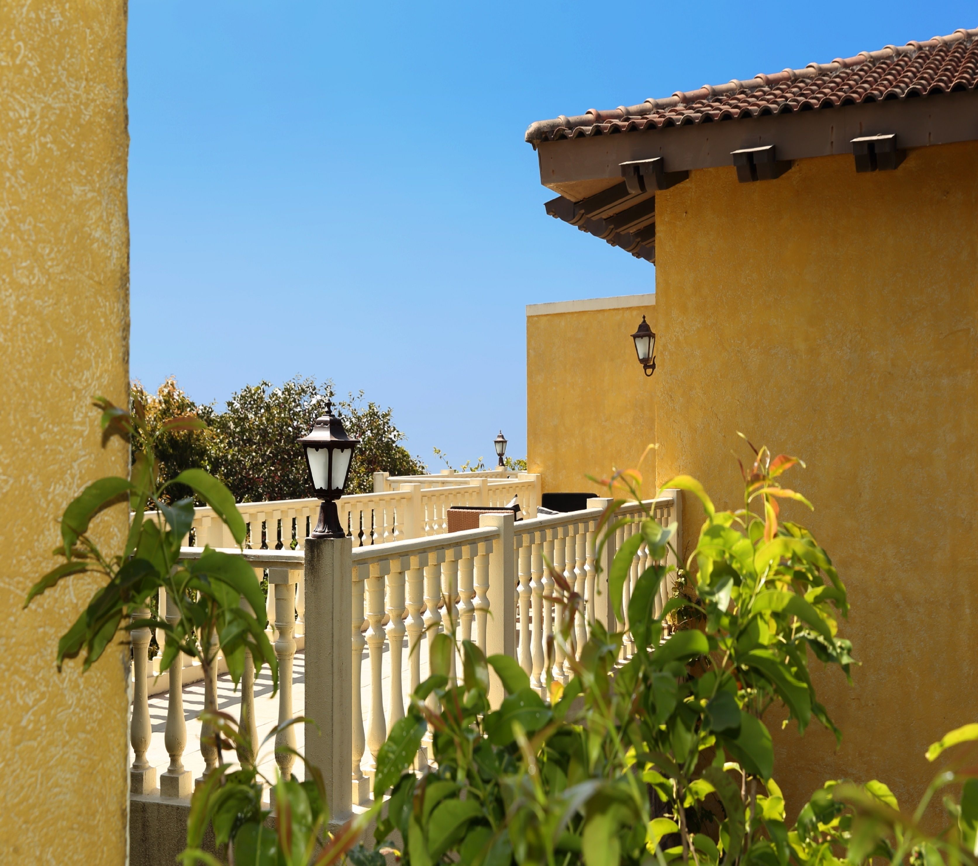 A yellow building with a white balcony railing and a tiled roof.