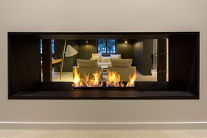 Una sala de estar moderna con chimenea, un conjunto de sofá y una lámpara.
