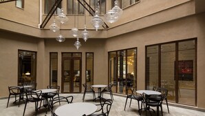 A spacious indoor area with multiple tables and chairs arranged for dining, large windows providing natural light, and a modern chandelier hanging from the ceiling. - Altiplanico Bellas Artes (Santiago)
