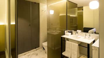 A modern bathroom with a glass-enclosed shower, a white toilet, and a vanity with a mirror.
