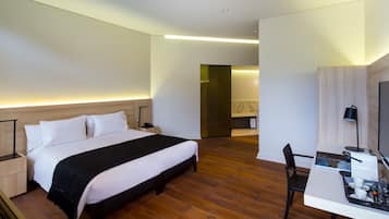 A modern hotel room with a large bed, a desk with a chair, and a television.