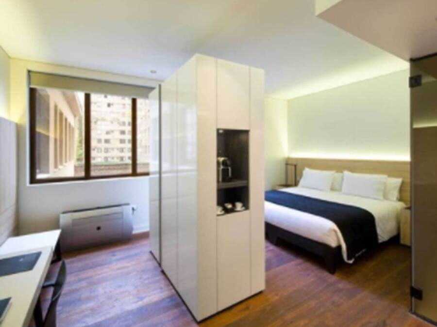 Una habitación de hotel moderna con cama, armario, escritorio y ventana.