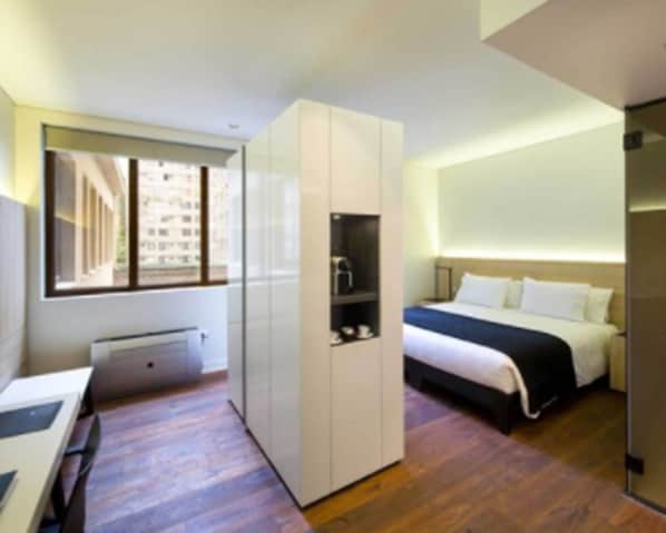 Una habitación de hotel moderna con cama, armario, escritorio y ventana.