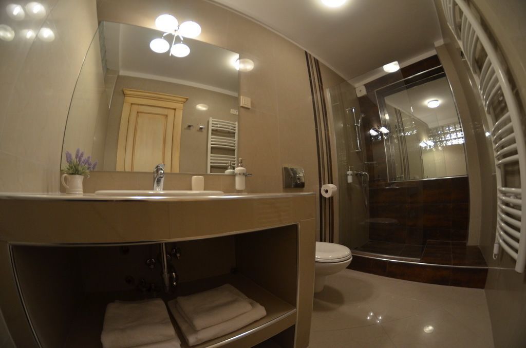 A modern bathroom with a large mirror, a sink, and a toilet.