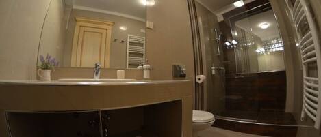 A modern bathroom with a large mirror, a sink, and a toilet.