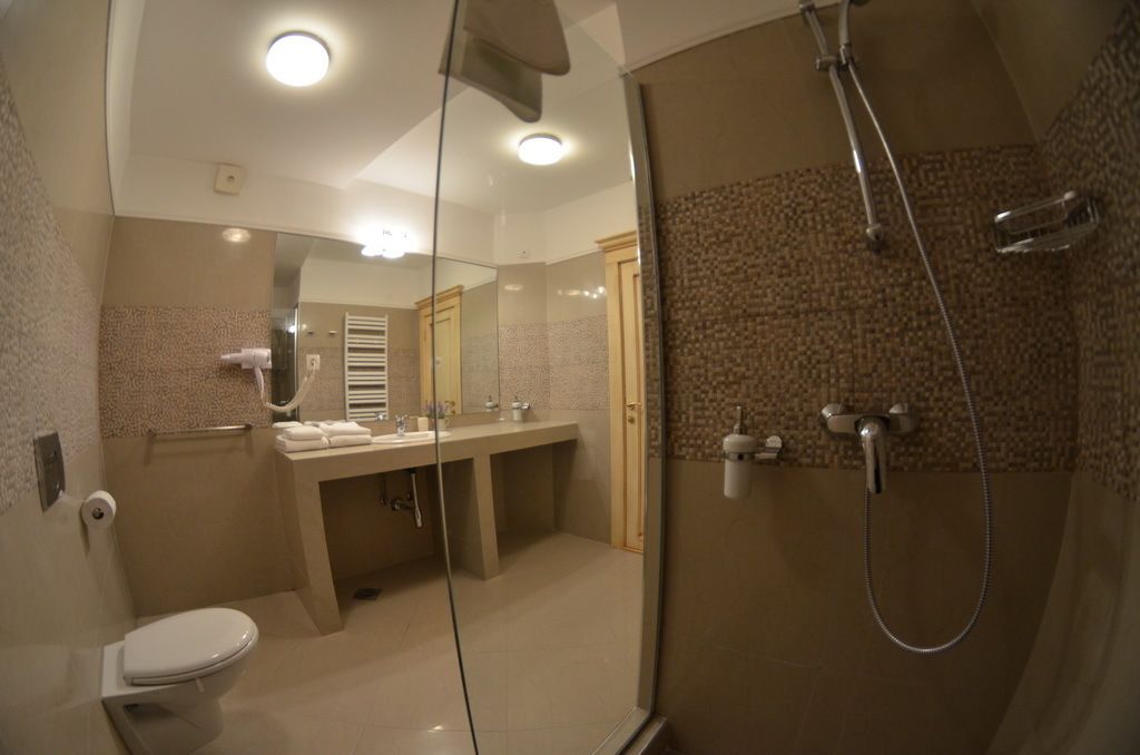 A modern bathroom with a glass-enclosed shower, a toilet, and a vanity with a mirror.