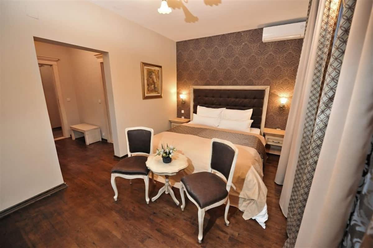 A hotel room with a large bed, two chairs, a small table, and a nightstand.
