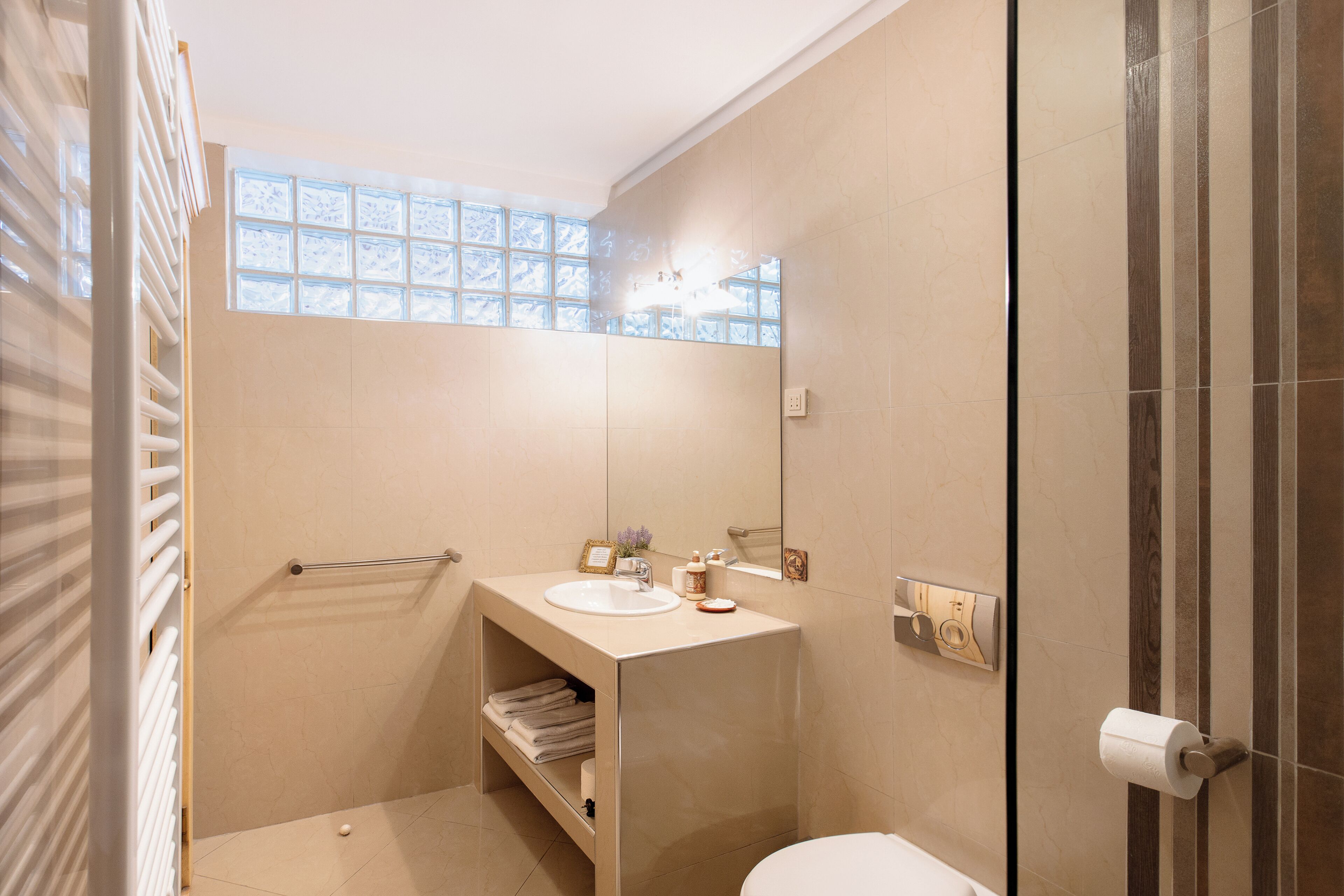 Un baño con ducha, lavabo, inodoro y perchero para toallas.
