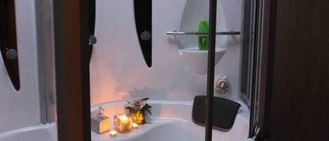 A modern bathroom with a glass-enclosed shower, a bathtub, and a vanity with a mirror.