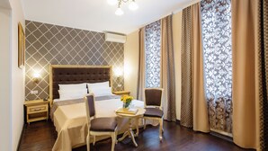 Ein Hotelzimmer mit einem großen Bett, einem kleinen Tisch mit Blumen, zwei Stühlen und einem Nachttisch.