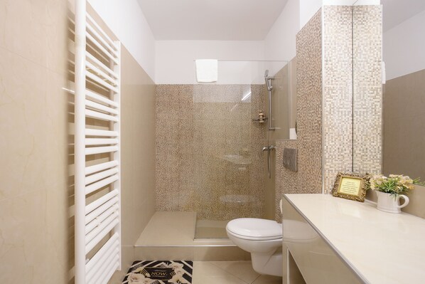 A compact bathroom with a shower, toilet, and a vanity with a mirror.