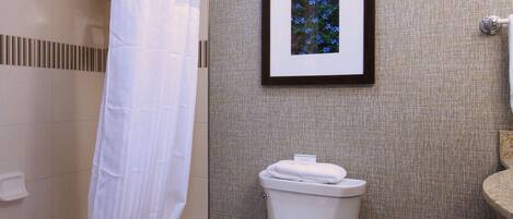 A bathroom with a bathtub, toilet, and a framed picture on the wall.