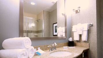 A hotel bathroom with a granite countertop, a sink, a mirror, and towels.