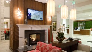 Eine moderne Lobby mit Kamin, einer Rezeption und einem Fernseher, der eine Karte zeigt.