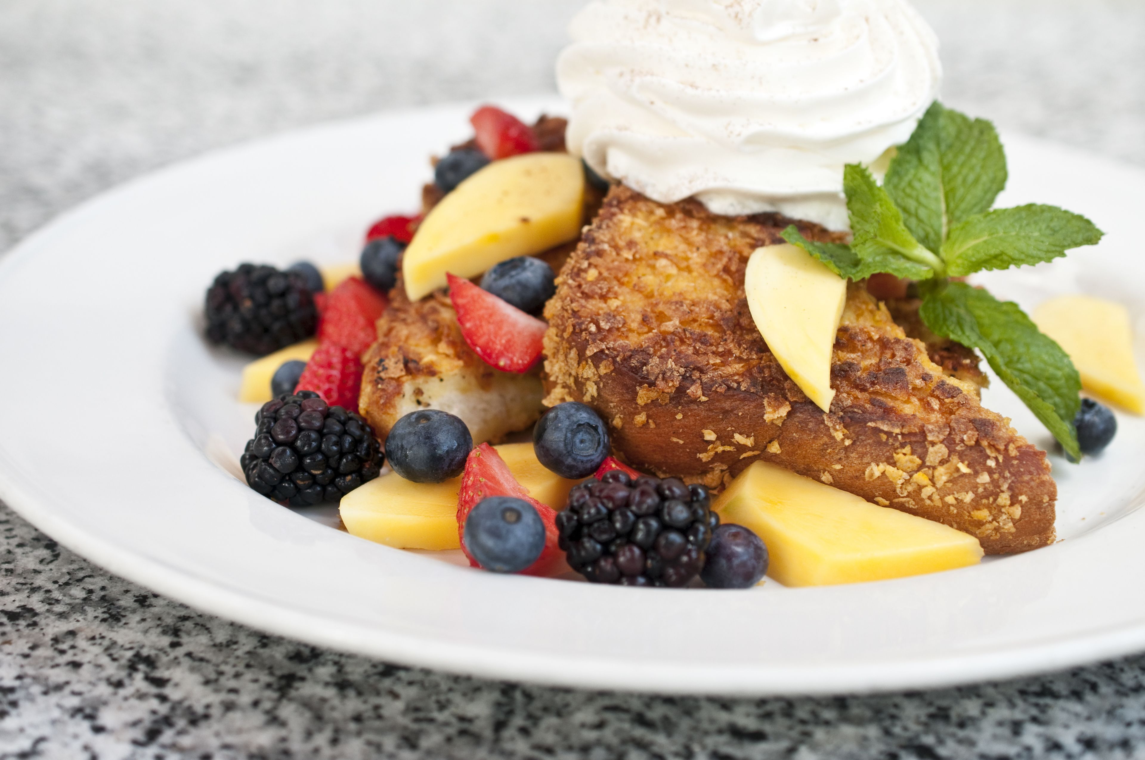 Una porzione di french toast con frutta e panna montata.