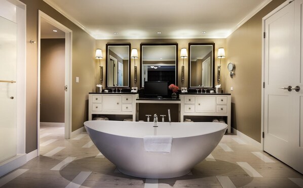 A modern bathroom with a freestanding bathtub, double sinks, and a large mirror above the vanity. - Golden Nugget Lake Charles (Lake Charles)