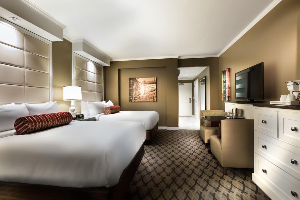Una habitación de hotel con una cama grande, un escritorio, televisión y vistas al exterior.