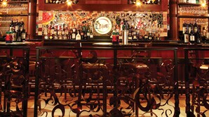 Un bar con un letrero que dice 'Grotto', estantes llenos de licores y una pared decorativa con un emblema circular.