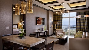 Una habitación de hotel moderna con zona de comedor, sofá y vistas al exterior.