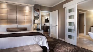 A modern hotel room with a large bed, a bedside table, a lamp, and a bathroom with a bathtub.