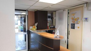Un área de recepción con mostrador, puerta y un cartel en la pared.