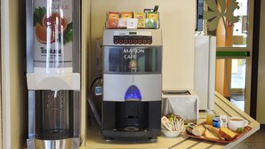 Una estación de café autoservicio con una máquina de café y una variedad de cápsulas de té y café.