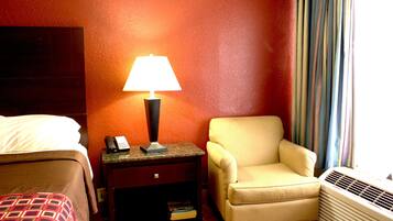 Une chambre d’hôtel avec un lit, une table de chevet avec une lampe, une chaise et un climatiseur.