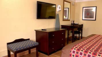 A hotel room with a bed, a desk, a chair, a dresser, a television, and a mirror.
