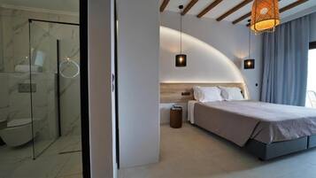 A modern bedroom with a curved ceiling, a large bed, a bedside table, and a hanging light fixture.