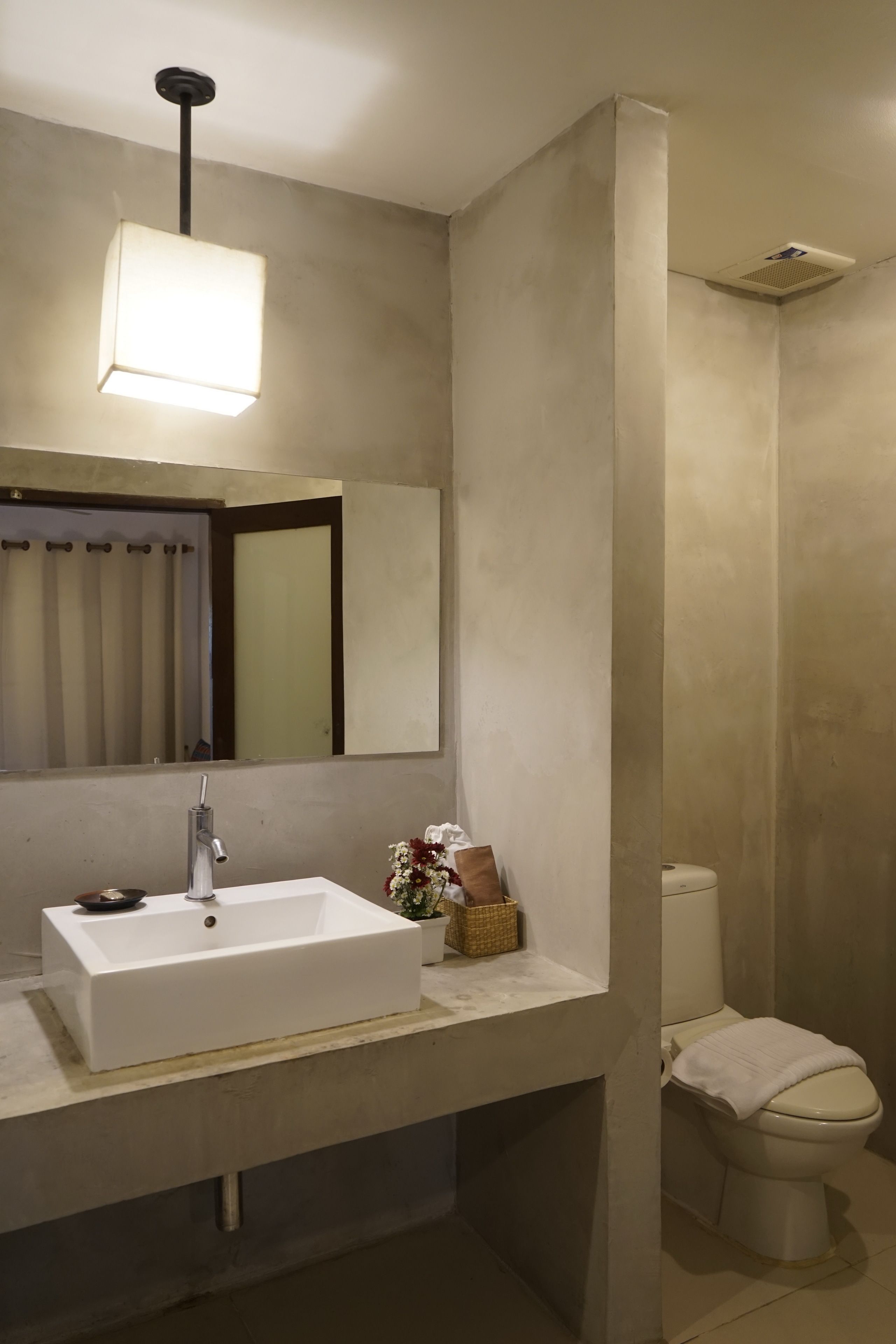 Un baño moderno con un lavabo blanco, un espejo y un inodoro.
