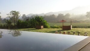 Una piscina infinita tranquila con vistas despejadas a un paisaje exuberante y montañas lejanas.
