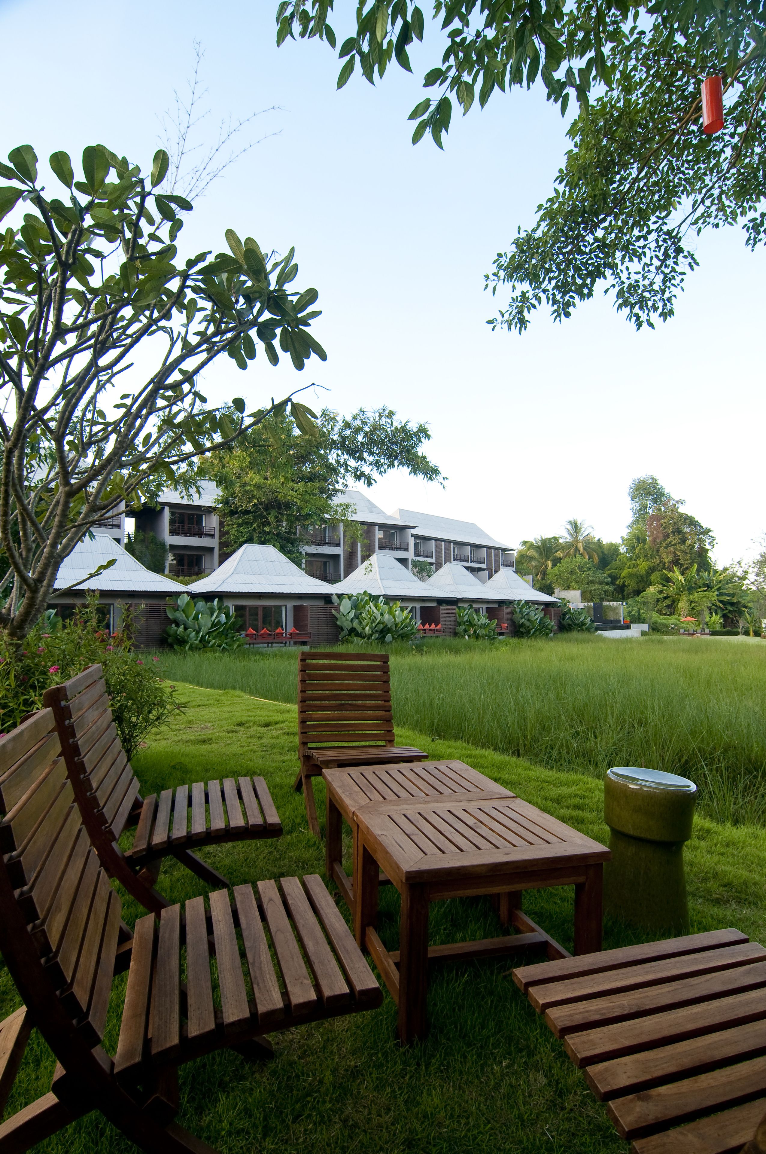 A courtyard with wooden furniture, a grassy area, and a building with multiple balconies.