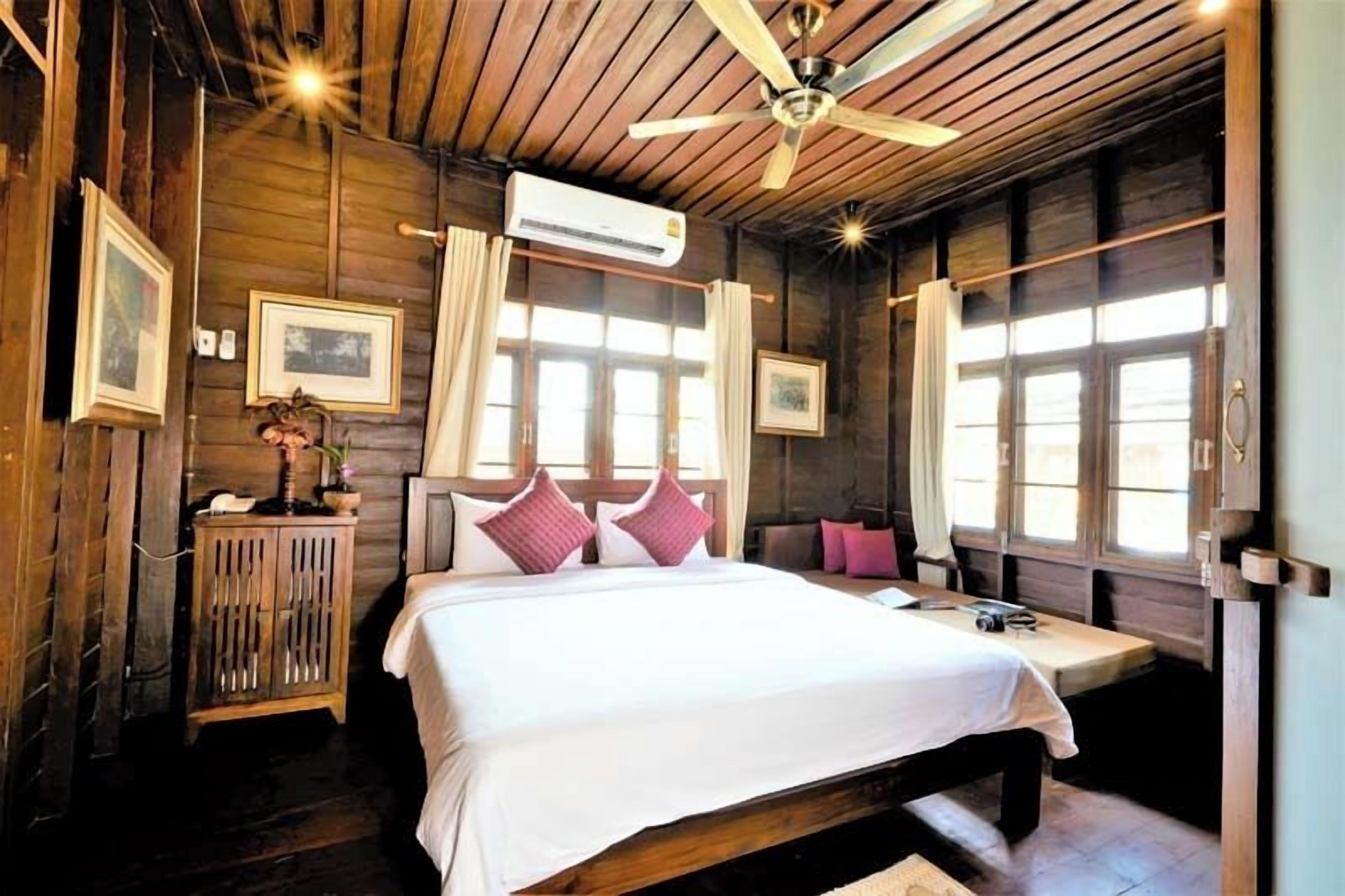 Una habitación de madera con una cama, un escritorio y un ventilador de techo.