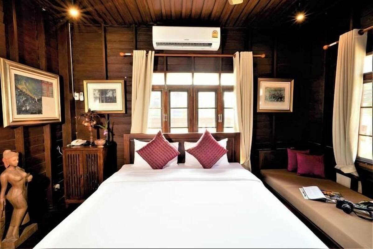 Una habitación de hotel con una cama grande, paredes de madera, una ventana con cortinas e imágenes enmarcadas.