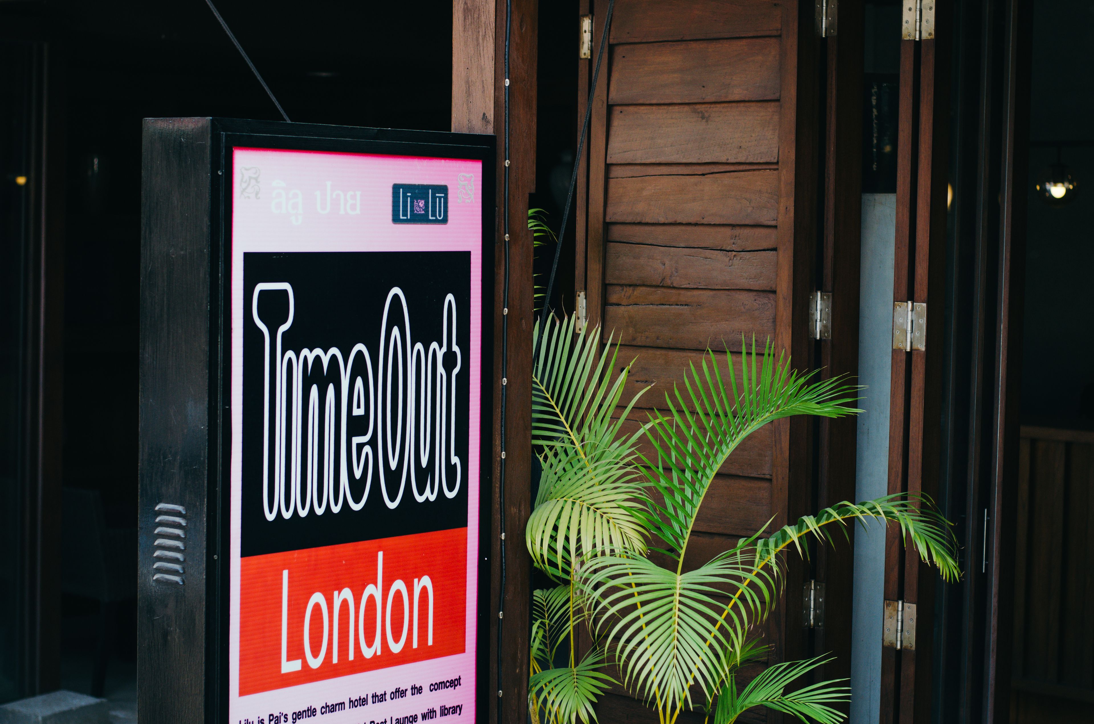 A sign for a hotel named "TimeOut London" with a modern design and a wooden door in the background.