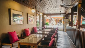 A restaurant with wooden tables and chairs, red cushions, and hanging pendant lights. - LILU PAI (Pai)
