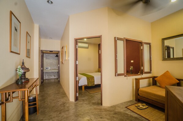 Habitación de hotel compacta con cama, una zona de estar pequeña, un escritorio y un espejo.