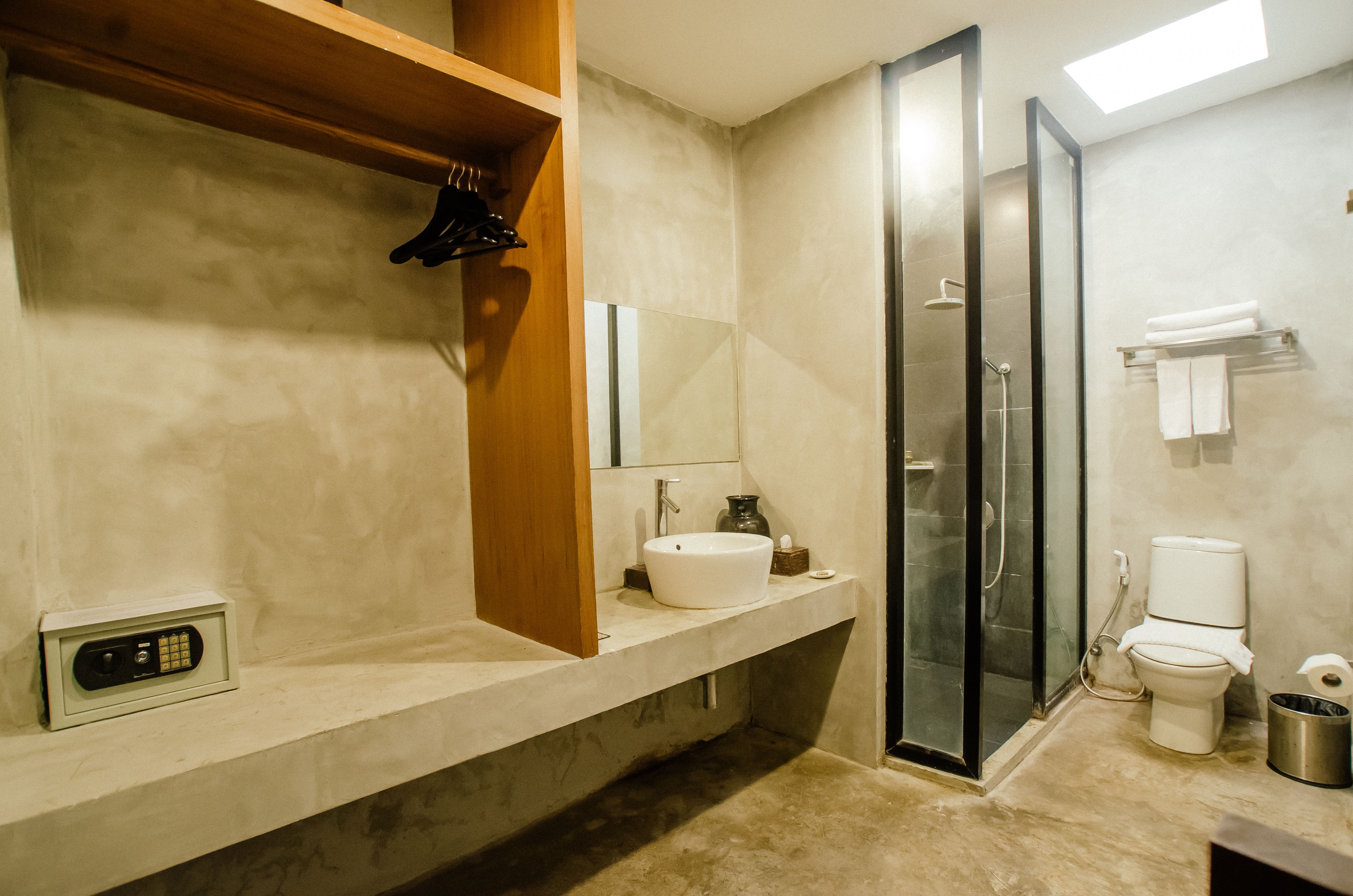 A modern bathroom with a large mirror, a sink, a toilet, and a shower area.