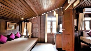 A wooden cabin-style room with a bed, a small table, and a window. - LILU PAI (Pai)