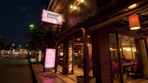 A hotel entrance with a signboard, indoor seating area, and a visible staircase. - LILU PAI (Pai)