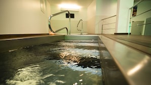 Una piscina interior moderna con agua cristalina, barandillas de metal y un ambiente bien iluminado.