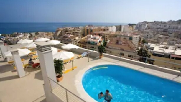 Una piscina en la azotea con vistas a la ciudad y al mar.