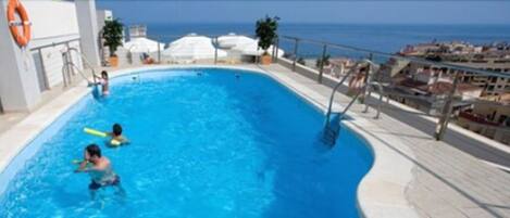 Alberca al aire libre, sombrillas en la alberca y camastros