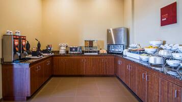 A modern kitchen with a coffee station, microwave, and various food dispensers.