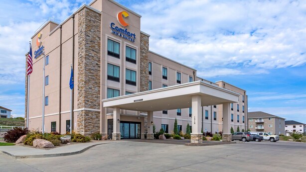 Un hotel Comfort Inn & Suites con fachada de piedra, varios pisos y entrada cubierta.
