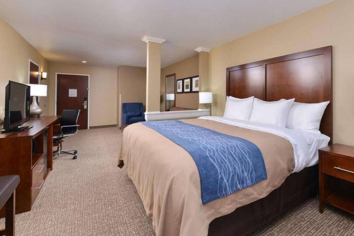 Une chambre d’hôtel avec un grand lit, un bureau avec un ordinateur, une chaise et une télévision.